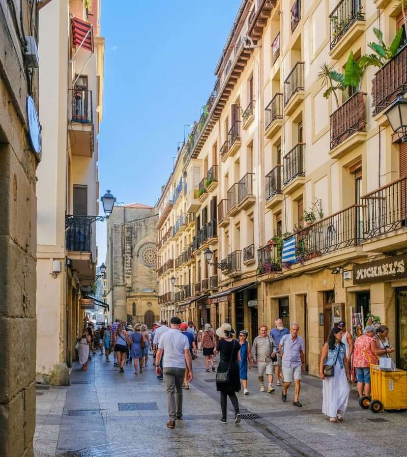 Tourists exploring a lively street with shops and historical buildings.