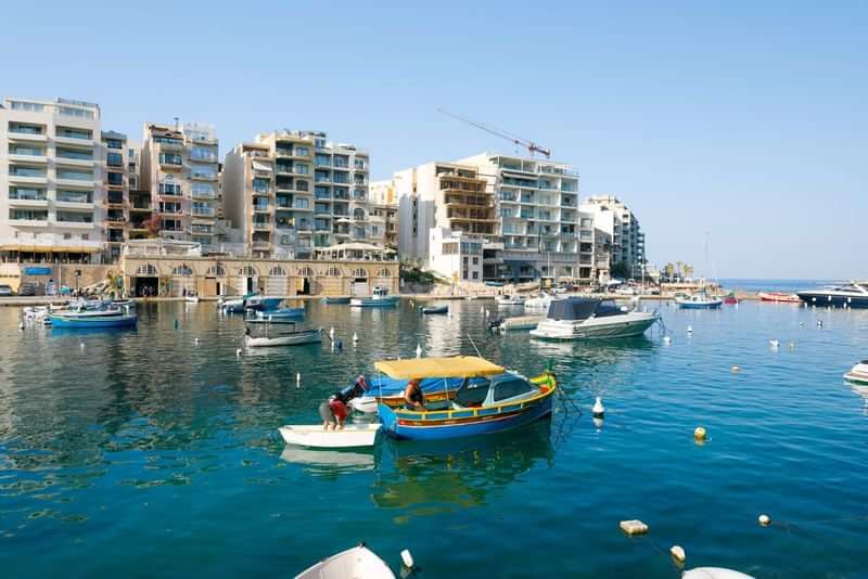 Havenstad aan de kust met boten en moderne appartementen.