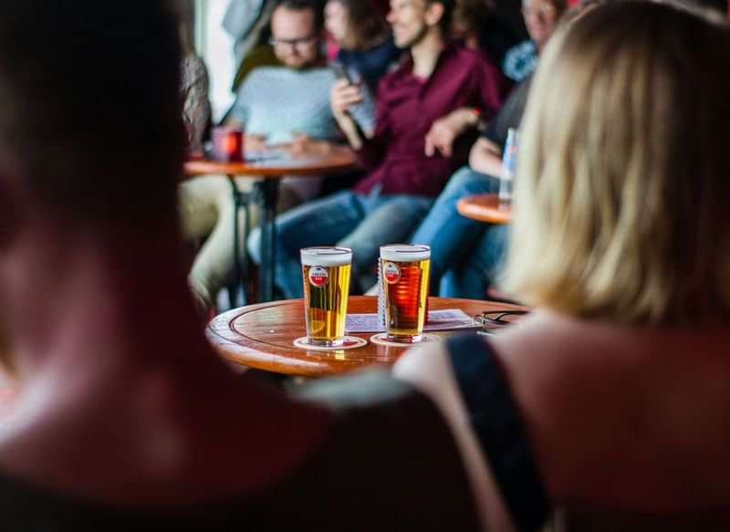 People enjoying drinks at a social gathering, possibly practicing language skills.