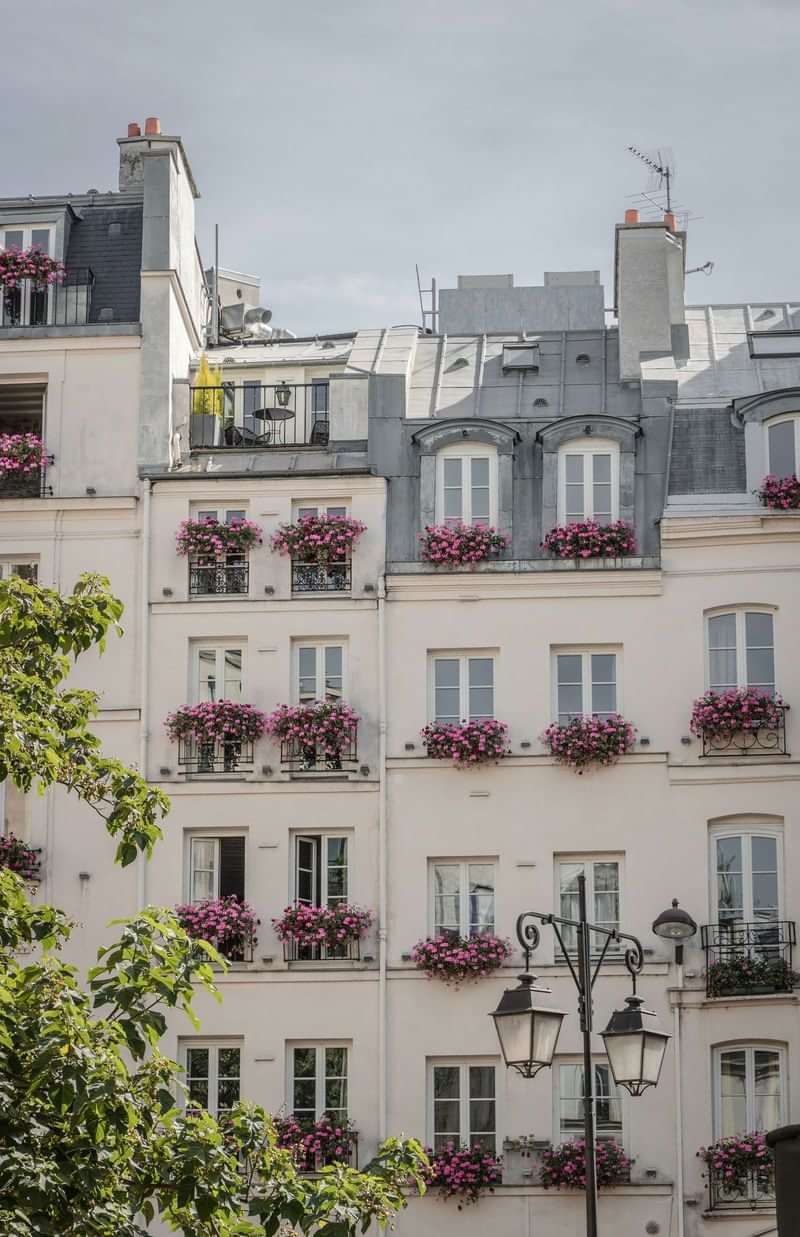 Parisian building with flower-filled balconies, classic French charm.