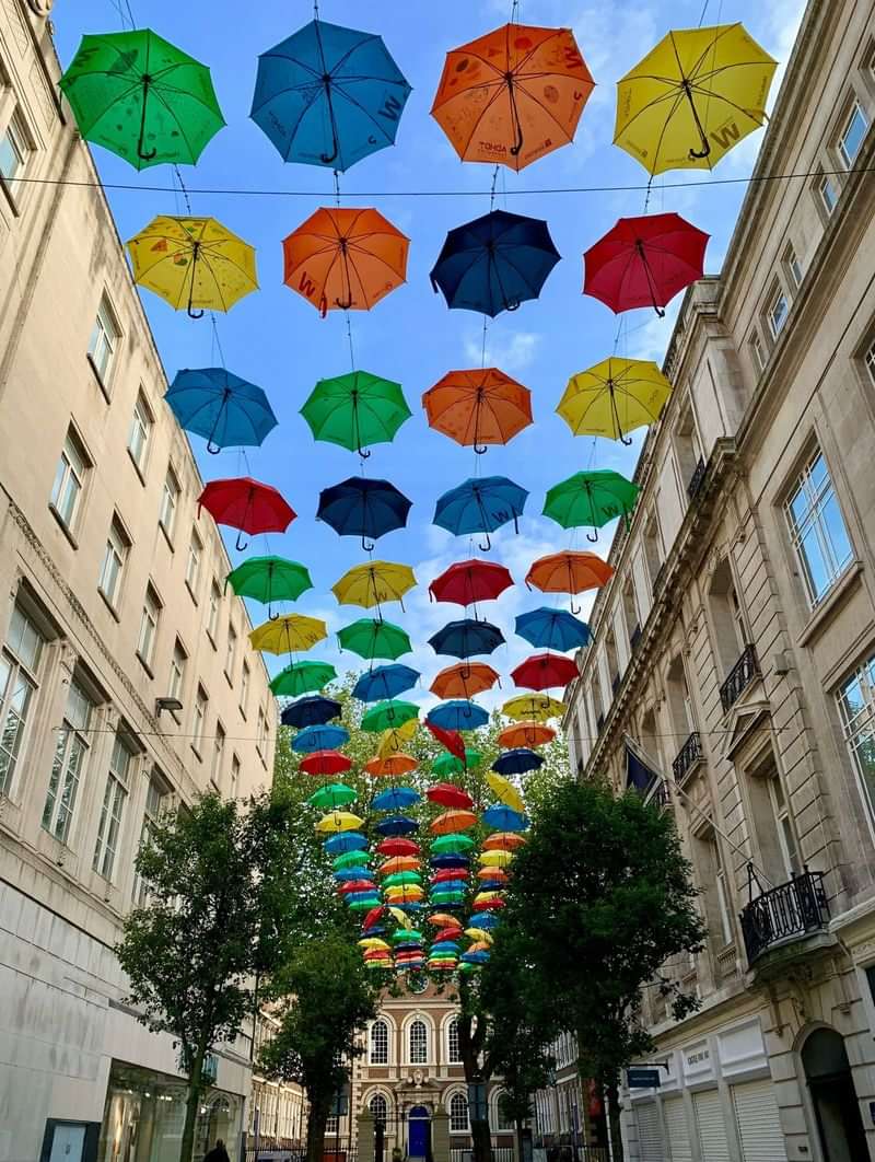 Colorful umbrellas hanging above a street in a European city.