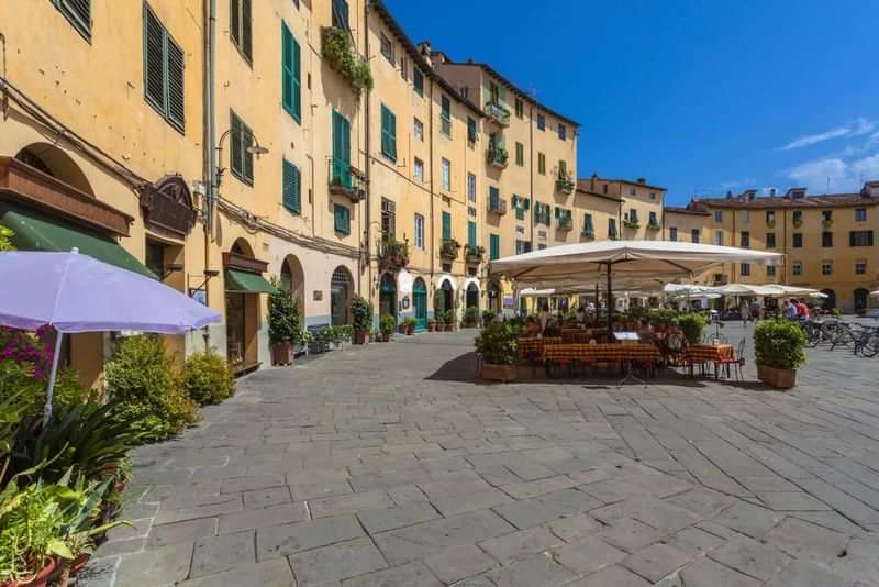 Italiaans plein met terrassen en restaurants, prachtige oude gebouwen, zonnige dag.