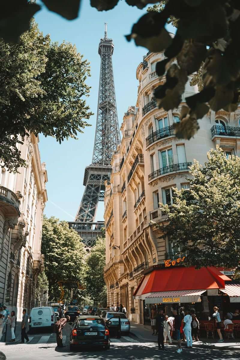Eiffel Tower view; Parisian street with people and cafe. French experience.