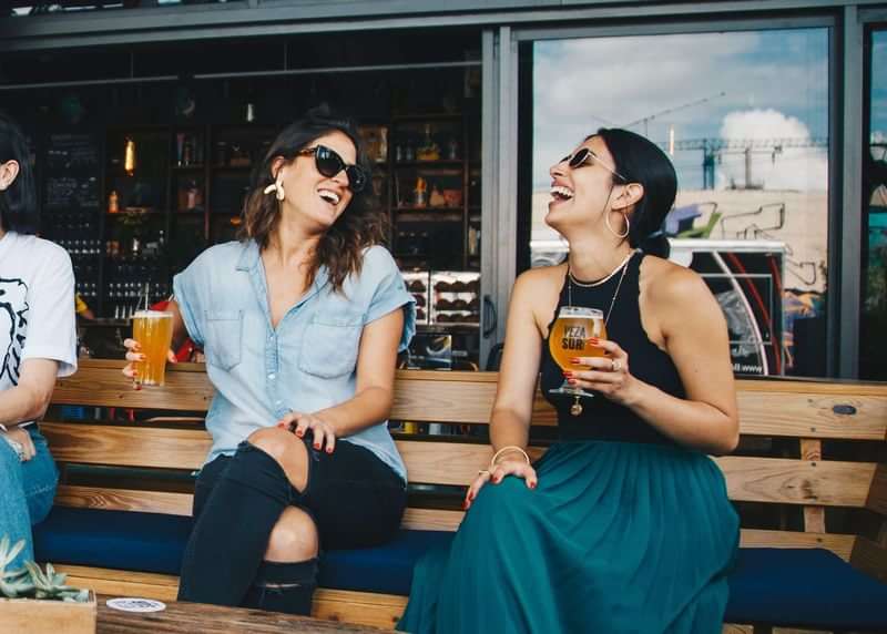 Vrienden genieten van drankjes en lachen tijdens taalreis in een café.
