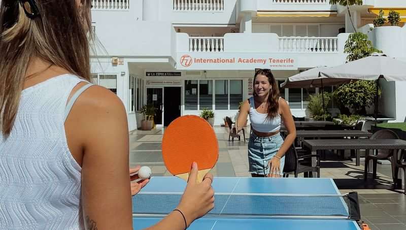 Playing table tennis at a language academy on a sunny day.