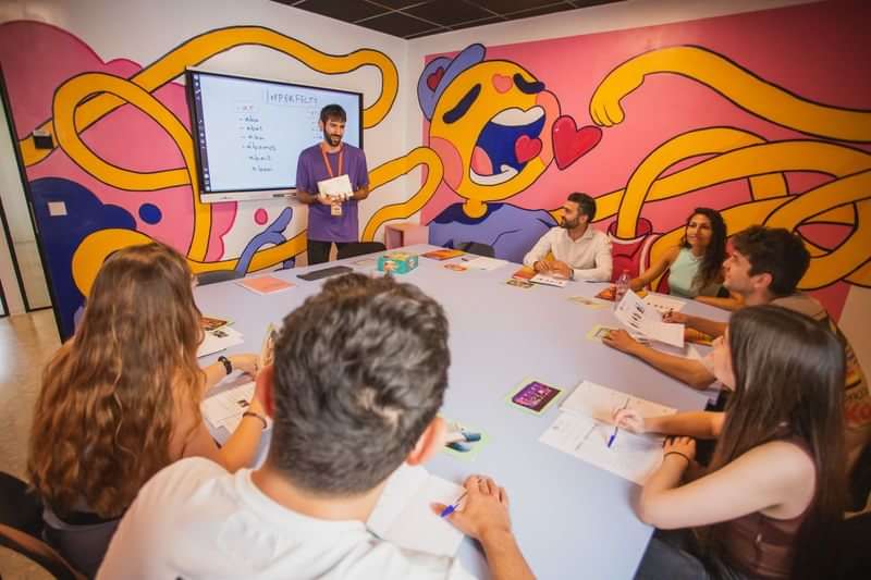 Language class with students and teacher, colorful mural, interactive learning.