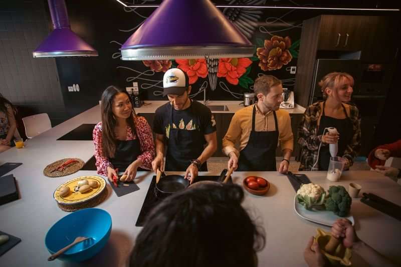 Taalreis deelnemers koken samen tijdens een workshop in een groepskeuken.