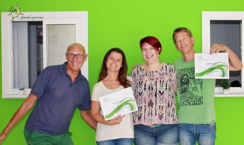 Vier mensen poseren met certificaten voor de taalcursus in Spanje.