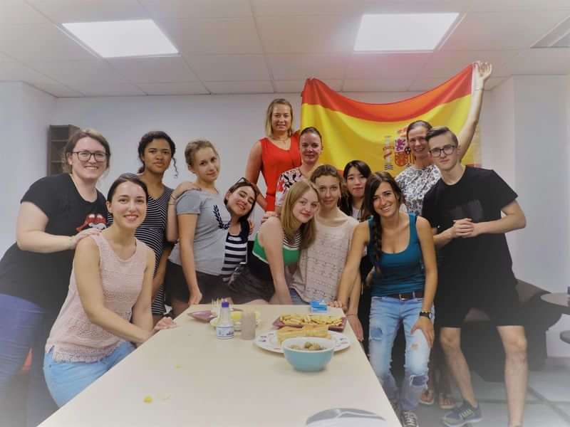 Groep studenten bij taalschool voor Spaanse les, Spaanse vlag op achtergrond.