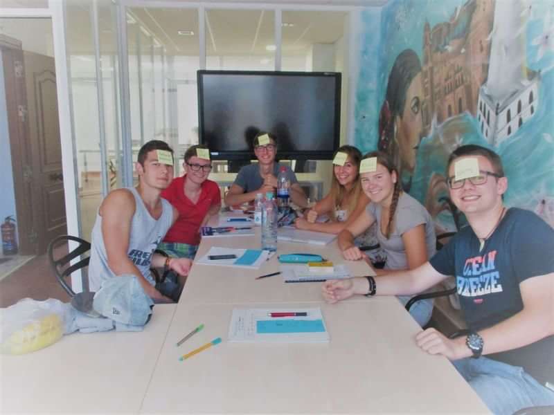 Taalreisgroep speelt een leerspel met post-its in een klaslokaal.