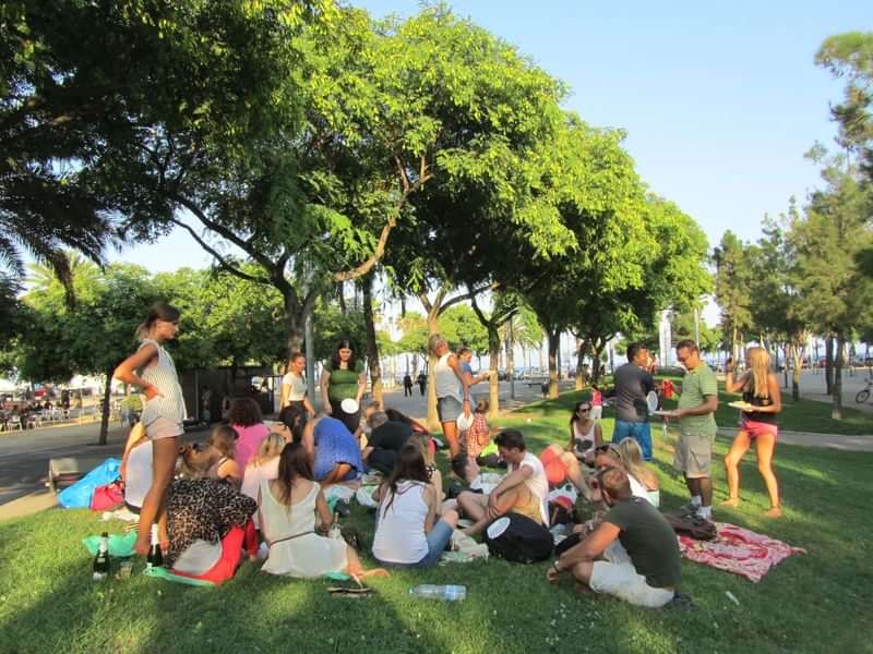 Groep jongeren verzameld in een park, wellicht een taalkampbijeenkomst.