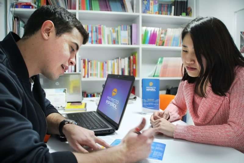 A student and tutor discussing a language lesson at a learning center.