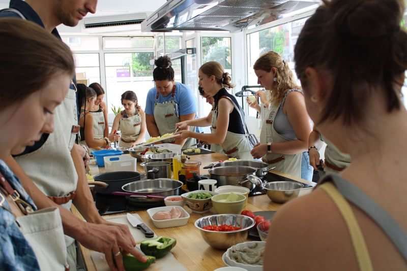 Groepskookles met internationale deelnemers die samen gerechten voorbereiden.