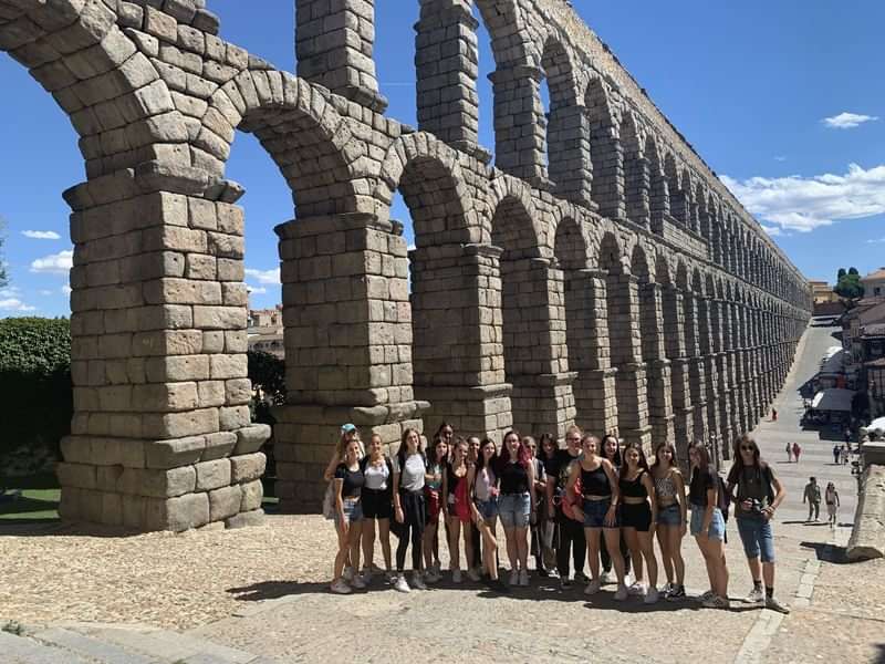 Group of students posed by an ancient aqueduct, exploring architecture and culture.