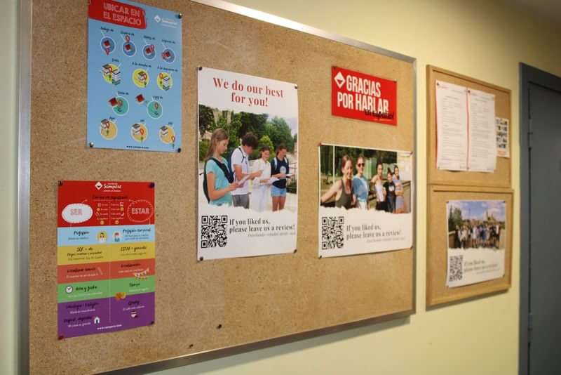 Mededelingenbord met verschillende posters over taalstudie en uitwisselingsprogramma's.