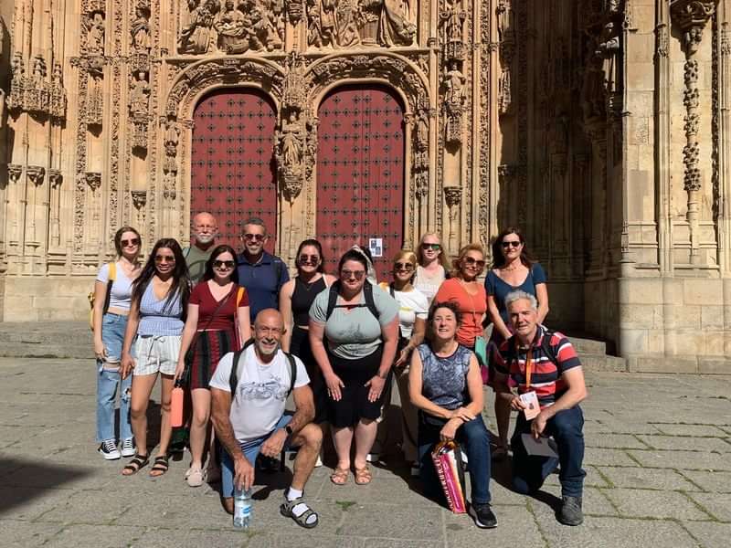 Groep toeristen poseert voor historische kathedraal tijdens een taalreis.