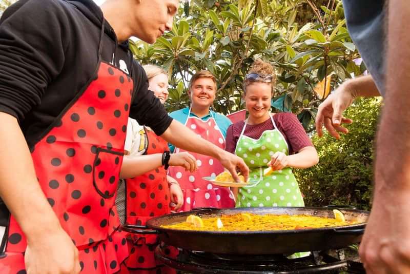 Een groep kookt samen paella tijdens een taalreis.