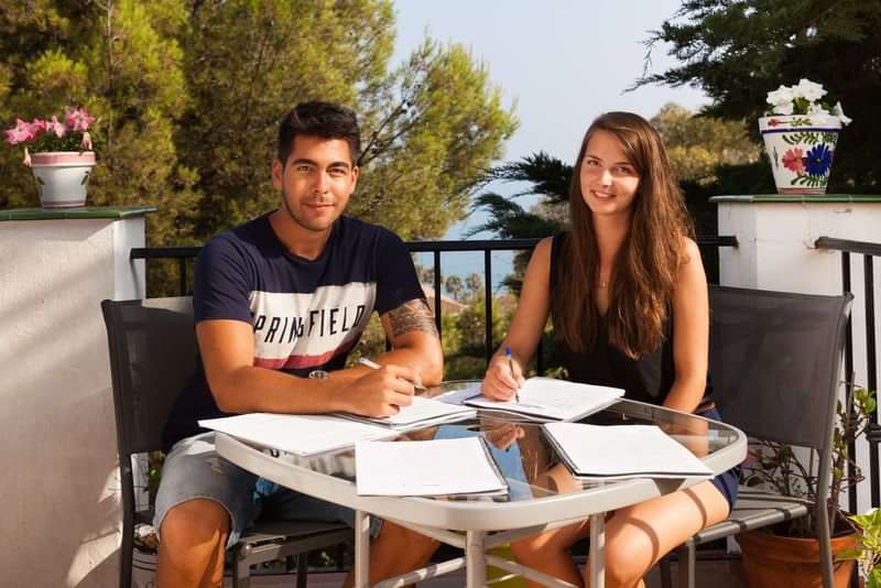 Twee jongeren studeren buiten, mogelijk tijdens een taalreis in het buitenland.