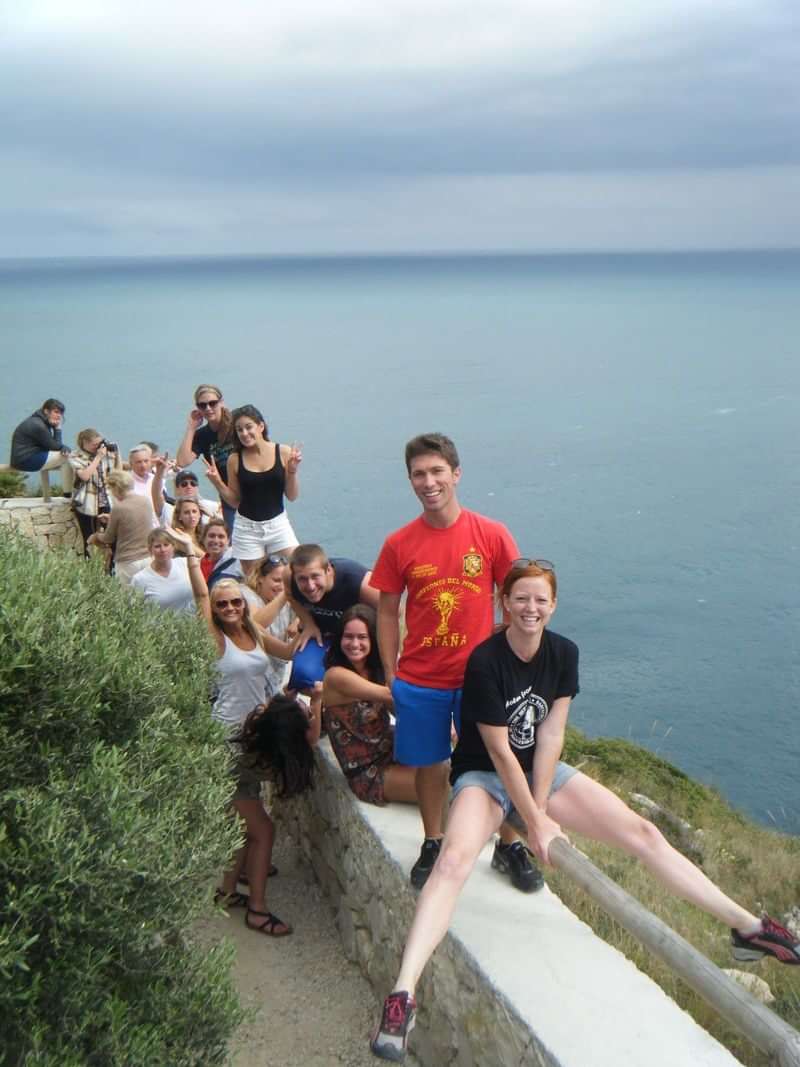 Een groep studenten geniet van een buitenactiviteit bij een kustlijn.
