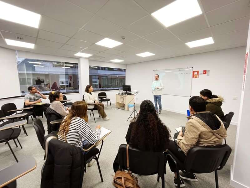 Students in a classroom, learning language for travel purposes, instructor teaching.