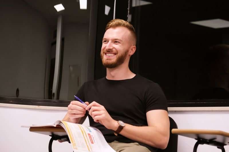 Man studying language, smiling in classroom during language immersion program abroad.