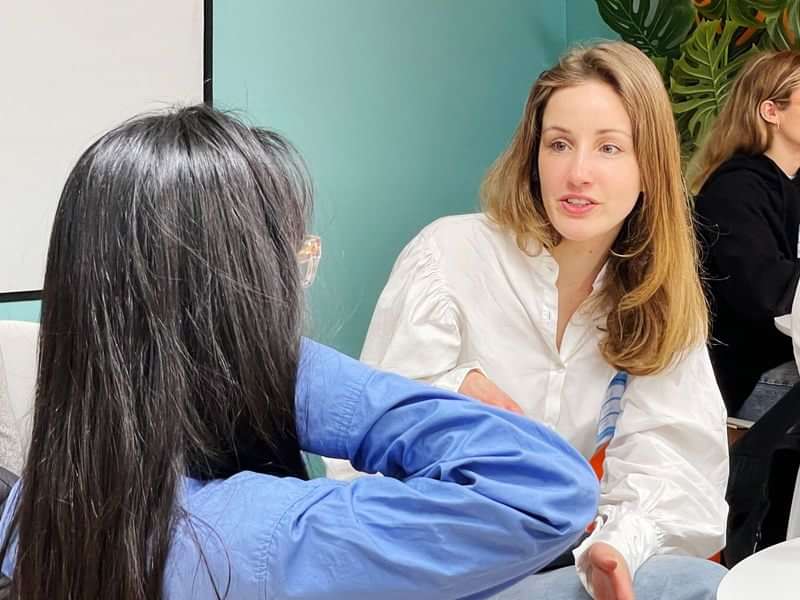 Two women engaging in a conversation, likely practicing language skills.