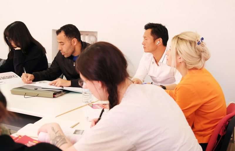 Groep studenten volgt een taalles in een klaslokaal.