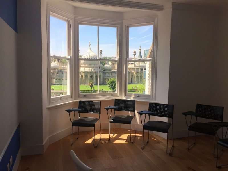 Bright room with chairs, overlooking a historic building, ideal for language learning.