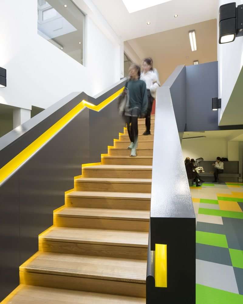 Modern building interior, students ascending stairs, educational setting, possibly language school.