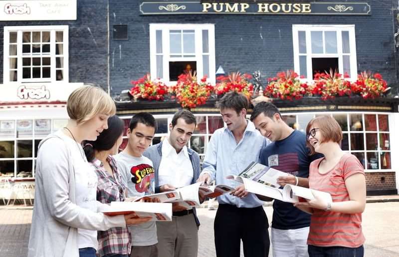 A group of students studying language travel materials outside in a town.