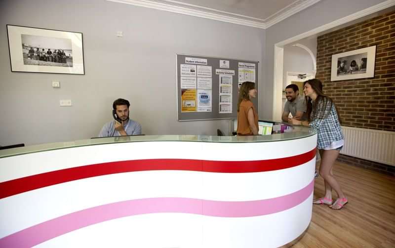Language school reception area with students discussing and receiving information.