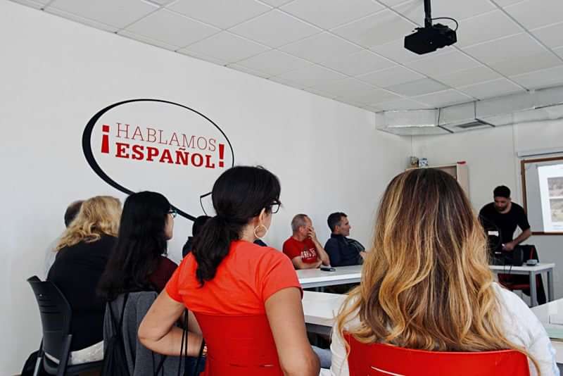 A group learning Spanish in a classroom setting, instructor present.