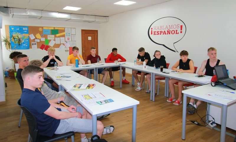 Studenten volgen een Spaanse taalles in een klaslokaal.
