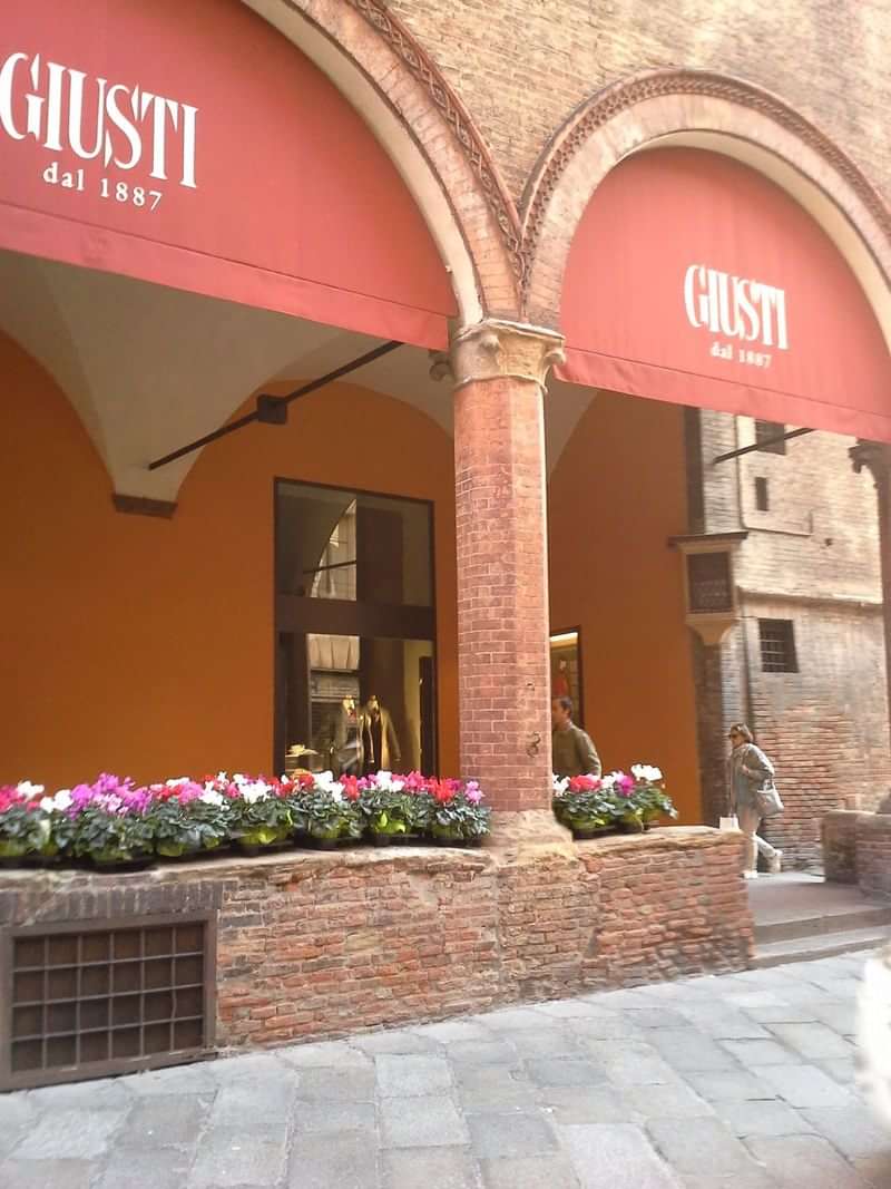 Een historisch gebouw met bloemen en mensen in een Italiaanse straat.