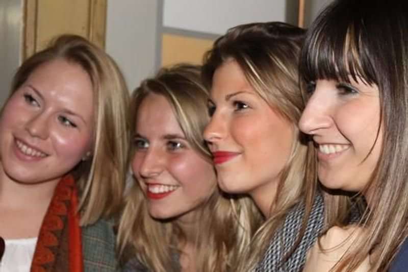 Vier lachende jonge vrouwen tijdens een taalcursus in Nederland.