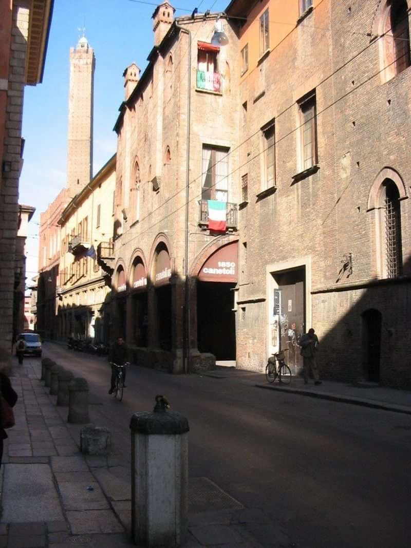 Historic Italian street with flag, language immersion, cultural exploration, brick buildings.