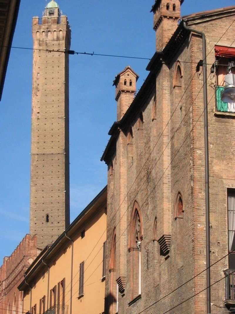 Een middeleeuwse toren met bakstenen gebouw ernaast in Italië.