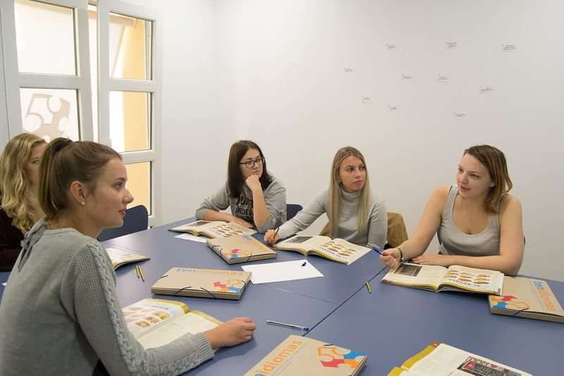 Studenten volgen een taalles in een kleinschalige klasomgeving.