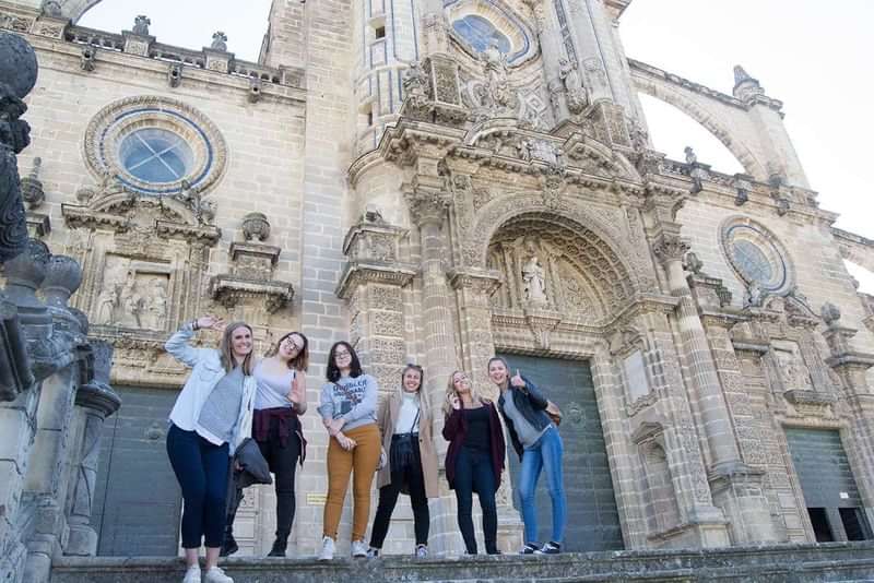 Studenten poseren voor een historische kathedraal tijdens hun taalreis.