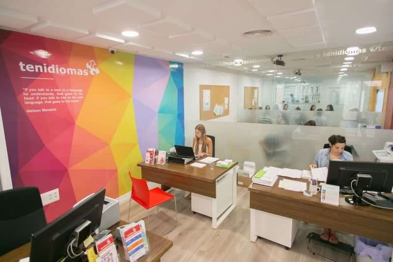 Reception area of a language school with colorful wall design and staff.