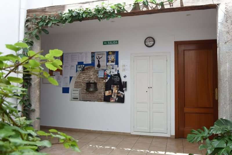 Language school's bulletin board and clock in courtyard setting.