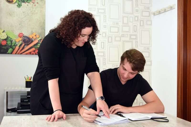 A student receiving language tutoring assistance from a teacher.