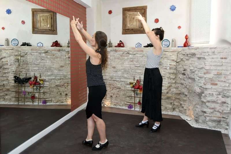 Dansles in een studio, twee vrouwen oefenen hun bewegingen.