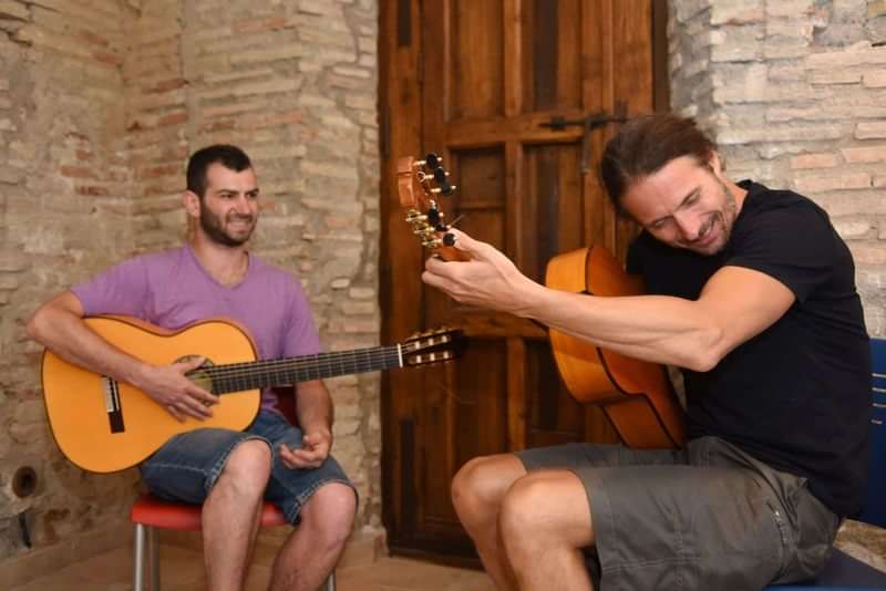 Two people practicing Spanish guitar in a cultural exchange setting.