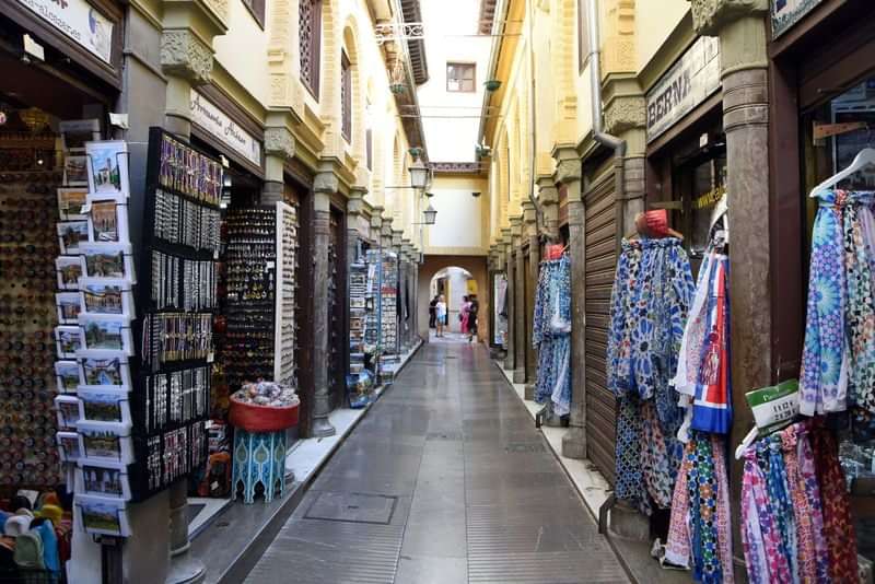 Narrow alley with colorful shops selling local souvenirs and garments.