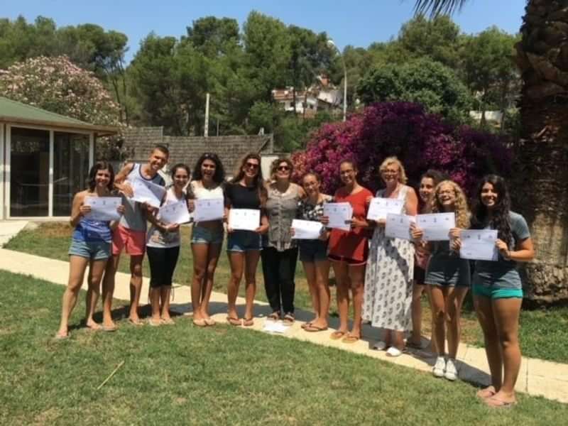 Group holding certificates outdoors, likely after a language travel program completion.