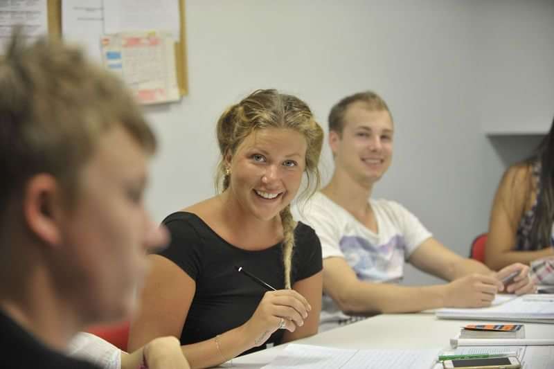 Language students in a classroom, engaging in a lesson, notebooks open.