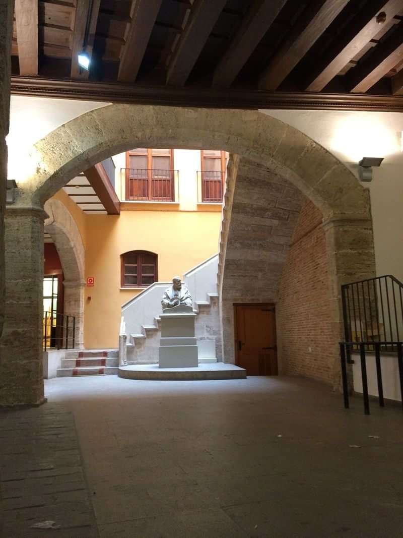 Historical courtyard with a statue, arched ceilings, steps, in a cultural setting.