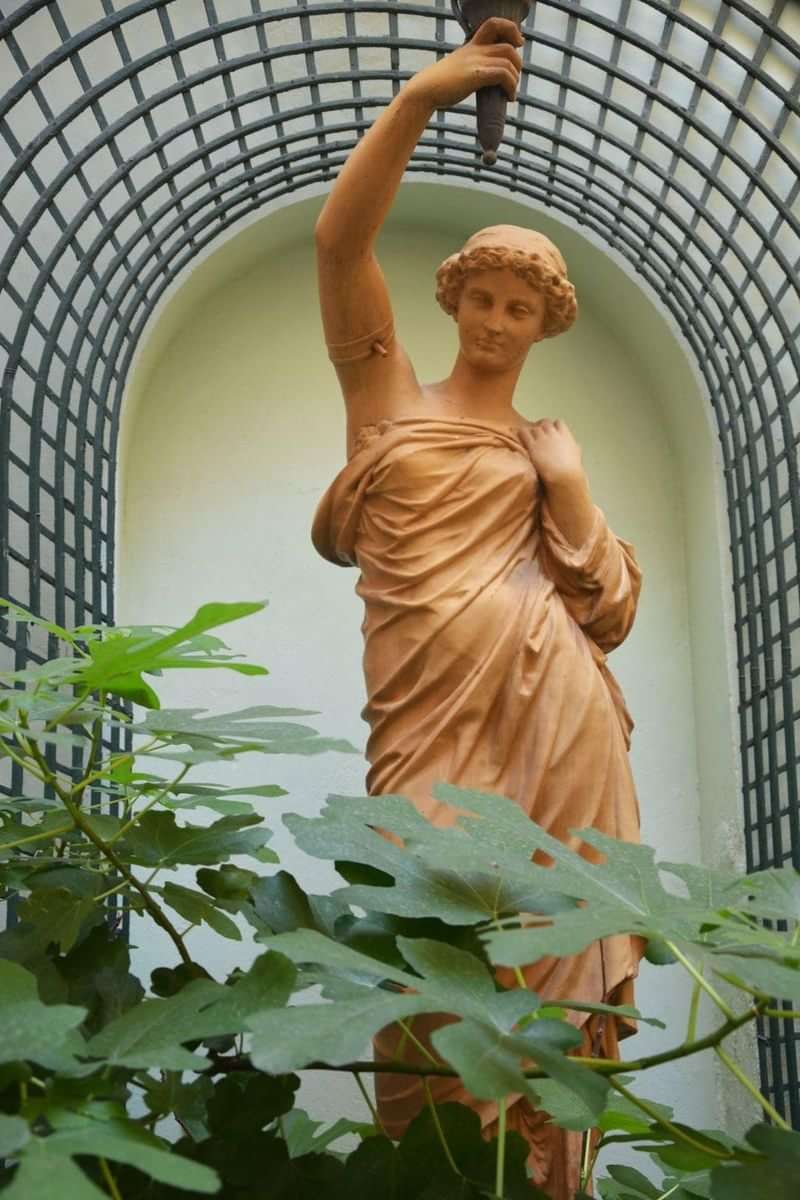 Een klassieke beeldhouwerkunst in een weelderige tuin.