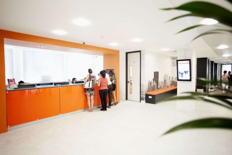 Language school reception area with students, vibrant modern ambiance.